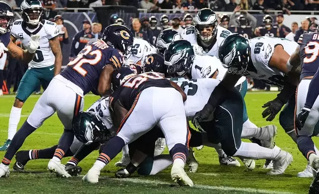 Philadelphia Eagles quarterback Jalen Hurts (1) runs the ball for a touchdown as Chicago Bears' Xavier Woods (32), Grady Jarrett (50) and others attempt to make the stop during the first half of an NFL football game in Chicago, Monday, Sept. 28, 2026. (AP Photo/David Banks)