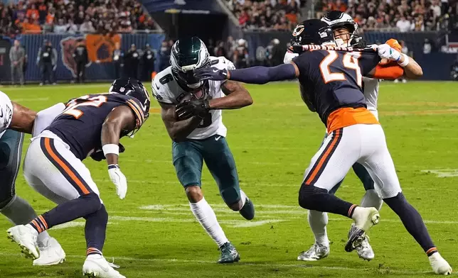Philadelphia Eagles wide receiver DeVonta Smith (6) runs the ball as Chicago Bears' Xavier Woods (32) an Malik Muhammad II (24) combine to make the stop during the first half of an NFL football game in Chicago, Monday, Sept. 28, 2026. (AP Photo/David Banks)