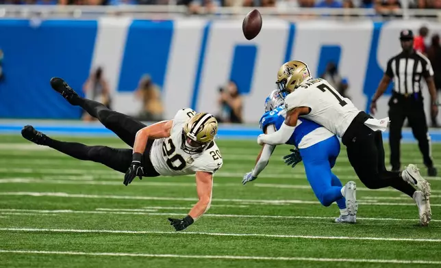 New Orleans Saints linebacker Pete Werner (20) and safety Jonas Sanker (7) break up a pass intended for Detroit Lions wide receiver Amon-Ra St. Brown in the first half of an NFL football game, Sunday, Sept. 13, 2026, in Detroit. (AP Photo/Paul Sancya)