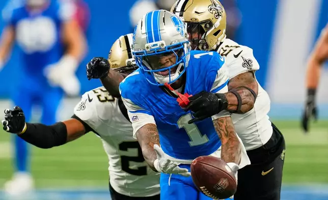 Detroit Lions wide receiver Jameson Williams (1) can't hold into a pass as he is defended by New Orleans Saints safety Justin Reid (21) and safety Julian Blackmon (23) in the first half of an NFL football game, Sunday, Sept. 13, 2026, in Detroit. (AP Photo/Paul Sancya)