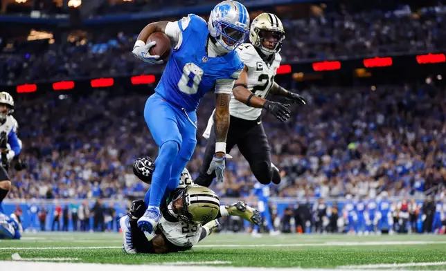 Detroit Lions running back Jahmyr Gibbs (0) carries against New Orleans Saints safety Julian Blackmon (23) and Justin Reid in the first half of an NFL football game, Sunday, Sept. 13, 2026, in Detroit. (AP Photo/Rey Del Rio)