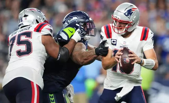 Seattle Seahawks nose tackle Byron Murphy II, center, pressures New England Patriots quarterback Drake Maye, right, as New England Patriots guard Alijah Vera-Tucker, right, moves in during the second half of an NFL football game, Wednesday, Sept. 9, 2026, in Seattle. (AP Photo/Lindsey Wasson)
