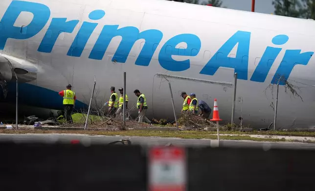 Workers inspect an Amazon cargo plane two days after it overshot a runway at Miami International Airport, Tuesday, Sept. 8, 2026, in Miami. (AP Photo/Rebecca Blackwell)