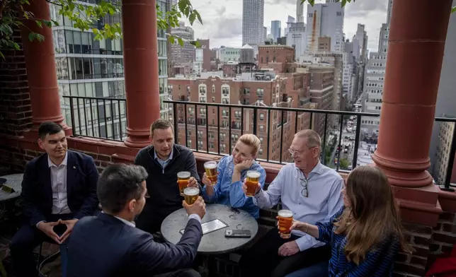 FILE - Denmark's Prime Minister Mette Frederiksen, center, Greenland's leader Jens-Frederik Nielsen, second left, and Greenland's Minister for Foreign Affairs Múte B. Egede, foreground left, have a beer with delegation members at a bar in Manhattan, New York after an agreement with the US was signed, Tuesday, Sept. 22, 2026. (Mads Claus Rasmussen/Ritzau Scanpix via AP, File)