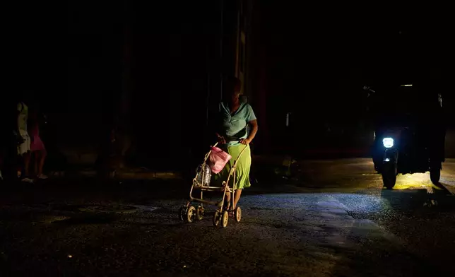 A woman pushes a cart across the street during a blackout in Havana, Cuba, Friday, Sept. 18, 2026. (AP Photo/Ramon Espinosa)