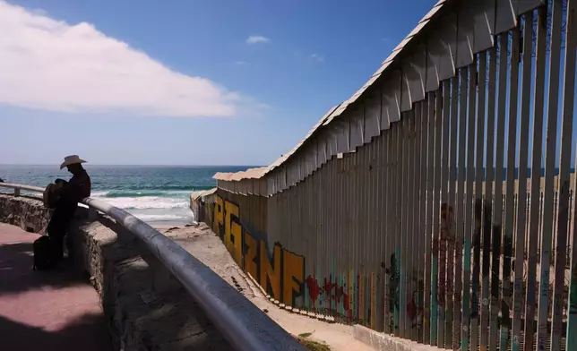 A musician, left, waits to play for visitors along the border walls separating the United States from Mexico near where it ends at the Pacific Ocean Tuesday, Sept. 15, 2026, in Tijuana, Mexico. (AP Photo/Gregory Bull)