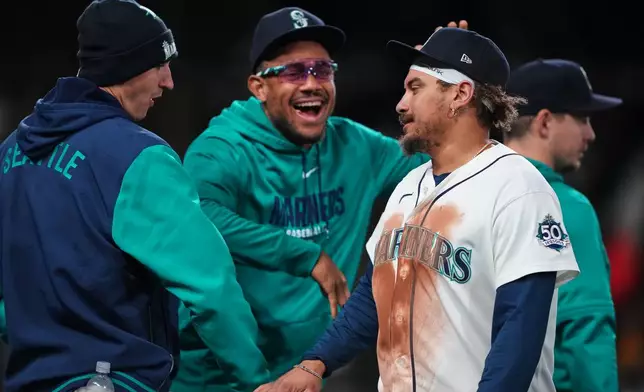 Seattle Mariners' Julio Rodríguez, center, greets Josh Naylor, right, as they celebrate a win over the Los Angeles Angels in a baseball game, Saturday, Sept. 26, 2026, in Seattle. (AP Photo/Lindsey Wasson)