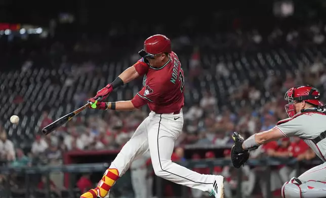 Arizona Diamondbacks' Lars Nootbaar, left, connects for a single as Philadelphia Phillies catcher J.T. Realmuto reaches for the ball during the first inning of a baseball game, Wednesday, Sept. 2, 2026, in Phoenix. (AP Photo/Ross D. Franklin)