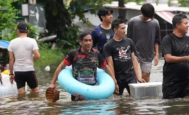 People wade through floodwaters after heavy rain in Bangkok, Thailand, Sunday, Sept. 27, 2026. (AP Photo/Sakchai Lalit)