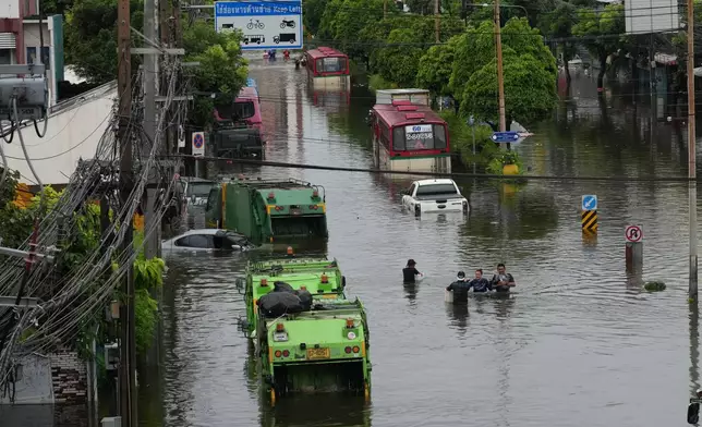 People wade through a flooded street after heavy rain in Bangkok, Thailand, Sunday, Sept. 27, 2026. (AP Photo/Sakchai Lalit)