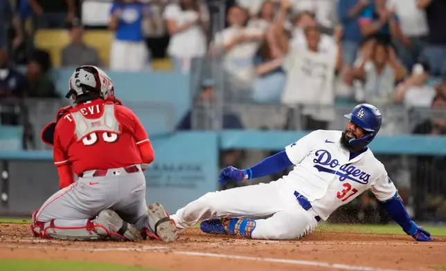 Los Angeles Dodgers' Teoscar Hernández, right, is tagged out by Cincinnati Reds catcher Jose Trevino as he tries to score on an inside-the-park home run during the third inning of a baseball game Tuesday, Sept. 8, 2026, in Los Angeles. (AP Photo/Mark J. Terrill)