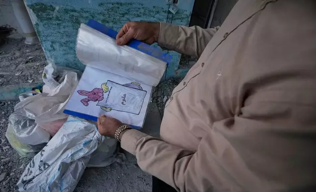 A volunteer holds a child's notebook recovered from the Shajareh Tayyebeh school, hit on Feb. 28 by a U.S. airstrike, in Minab, southern Iran, Monday, Sept. 7, 2026. (AP Photo/Vahid Salemi)