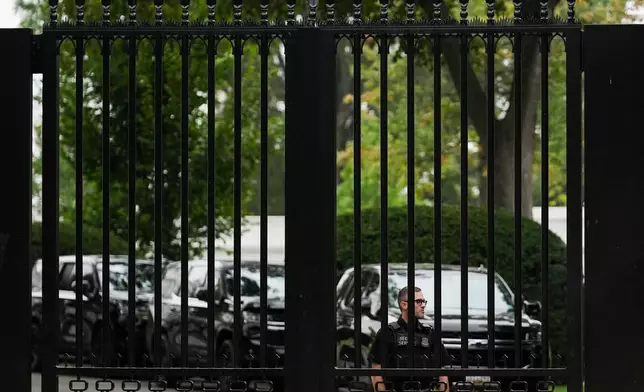 A U.S. Secret Service agent watches through a fence as President Donald Trump departs the White House en route to Trump National Golf Club, Sunday, Aug. 30, 2026, in Washington. (AP Photo/Julia Demaree Nikhinson)