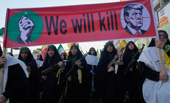 Women affiliated with Iran's Revolutionary Guard carry rifles as they march beneath a banner depicting U.S. President Donald Trump in crosshairs and reading "We will kill" during the state-organized "Janfada," or "Sacrifice for Iran," military-style parade in Tehran, Iran, Friday, Sept. 18, 2026. (AP Photo/Vahid Salemi)