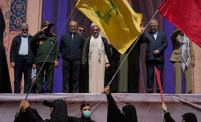 A flag of the Lebanese militant group Hezbollah is waved in front of Iranian President Masoud Pezeshkian, third from left, and other officials during the state-organized "Janfada," or "Sacrifice for Iran," military-style parade in Tehran, Iran, Friday, Sept. 18, 2026. (AP Photo/Vahid Salemi)