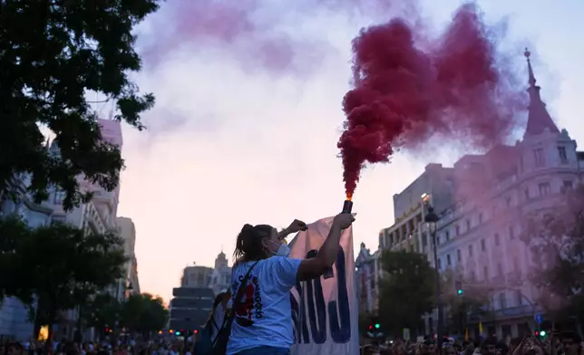 A woman holds a flare during a protest following the eviction last Wednesday of 87-year-old Maricarmen to demand stronger laws to protect renters at Puerta del Sol in Madrid, Spain, Saturday, Sept. 26, 2026. (AP Photo/Manu Fernandez)