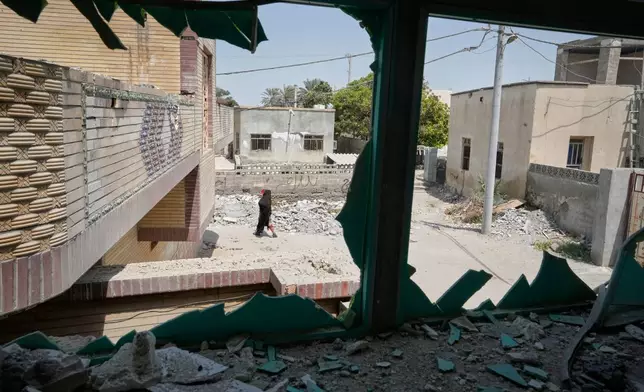 A person walks past debris, seen through a shattered window at the site of what Iranian media said was a U.S. strike on a home where a wedding celebration was being held late Tuesday, Sept. 1, in Kuhestak, southern Iran, Friday, Sept. 4, 2026. (AP Photo/Vahid Salemi)