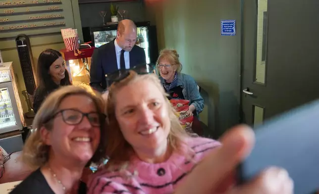 Customers take a selfie with their cellphone as Prince William visits ActOne, an independent, community-led cinema, to celebrate Britain's film industry in London, Tuesday, Sept. 22, 2026. (AP Photo/Kin Cheung, Pool)