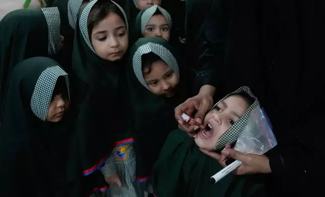 A health worker administers a polio vaccine to a child at a school in Lahore, Pakistan, Monday, Sept. 21, 2026. (AP Photo/K.M. Chaudary)