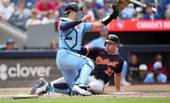 Toronto Blue Jays catcher Brandon Valenzuela (59) tries to tag out Detroit Tigers' Colt Keith (33) as he scores a run during the first inning of a baseball game in Toronto, Wednesday, Sept. 16, 2026. (Nathan Denette/The Canadian Press via AP)