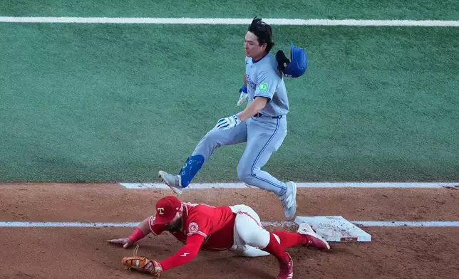 Texas Rangers first baseman Jake Burger, bottom, puts out Toronto Blue Jays' Brett Bateman on a groundout during the third inning of a baseball game Friday, Sept. 18, 2026, in Arlington, Texas. (AP Photo/Julio Cortez)