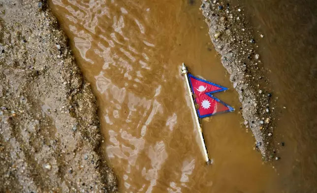 A Nepal flag lies on a muddy track near the banks of the Trishuli river in Dhading District, Nepal, Sunday, Aug. 30, 2026. (AP Photo/Niranjan Shrestha)