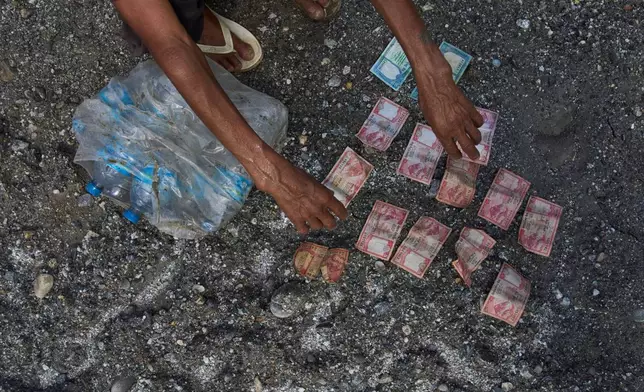 A man salvages a money and bottles of mineral water from his house affected by flash floods in Dhading District, Nepal, Sunday, Aug. 30, 2026. (AP Photo/Niranjan Shrestha)