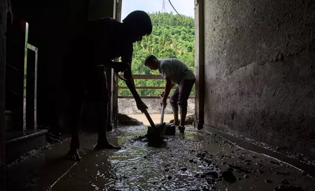 People clear mud and sand from a house brought by the Trishuli River during flash floods in Dhading District, Nepal, Sunday, Aug. 30, 2026. (AP Photo/Niranjan Shrestha)