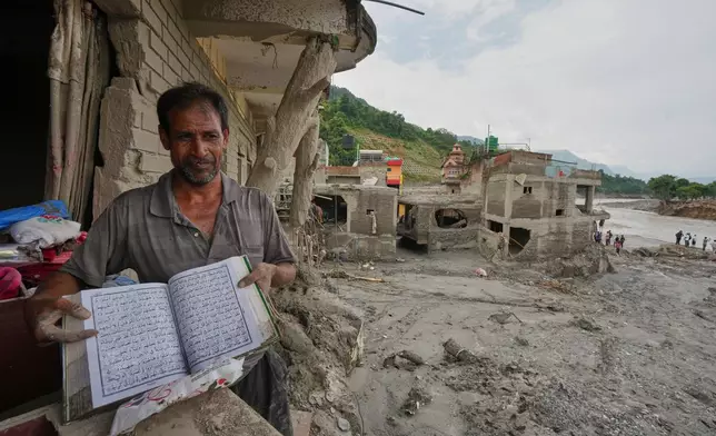 A resident shows a holy book as he salvages his belongings from damaged home filled with mud and debris in Devighat, in Nepal's Nuwakot district, Saturday, Aug. 29, 2026, following the Aug. 26 flash floods. (AP Photo/Rajesh Kumar Singh)