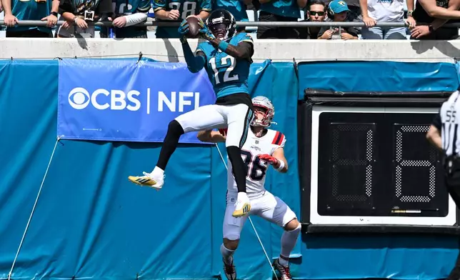 Jacksonville Jaguars wide receiver Travis Hunter (12) intercepts a pass intended for New England Patriots wide receiver Efton Chism III (86) in the first half during an NFL football game in Jacksonville, Fla., Sunday, Sept. 27, 2026. (AP Photo/Phelan M. Ebenhack)