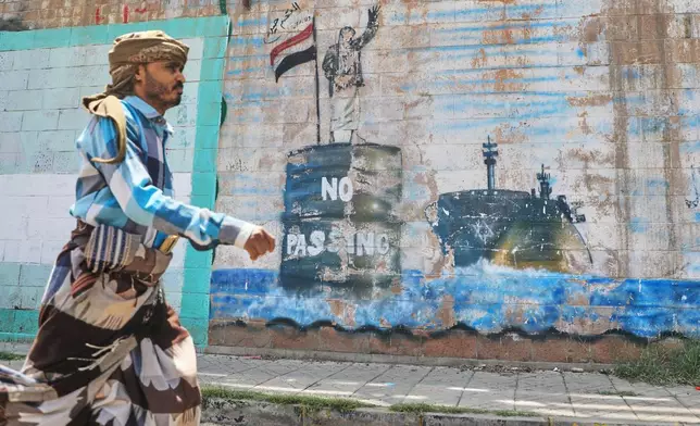 A man walks in front of a mural symbolising restrictions on shipping through the Bab el-Mandeb Strait, one of the world's key shipping lanes, in Sanaa, Yemen, Monday, Sept. 14, 2026. (AP Photo/Osamah Abdulrahman)