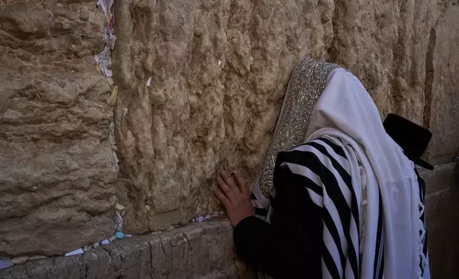 Covered in prayer shawl a Jewish man prays as he participates in a blessing during the holiday of Sukkot, at the Western Wall, the holiest site where Jews can pray, in the Old City of Jerusalem, Monday, Sept. 28, 2026. (AP Photo/Leo Correa)