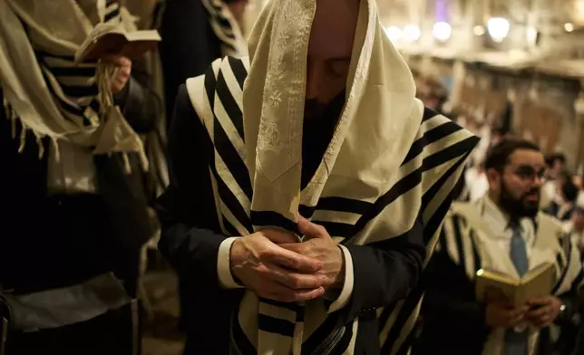 Orthodox Jewish men pray in front of the gate at Souq Al-Qattanin, or Cotton Merchants' Market, one of the entrances to the Al-Aqsa Mosque compound in the Old City of Jerusalem, Monday, Sept. 28, 2026, during morning prayers for the Jewish holiday of Sukkot. (AP Photo/Leo Correa)