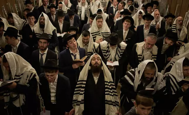 Orthodox Jewish men pray in front of the gate at Souq Al-Qattanin, or Cotton Merchants' Market, one of the entrances to the Al-Aqsa Mosque compound in the Old City of Jerusalem, Monday, Sept. 28, 2026, during morning prayers for the Jewish holiday of Sukkot. (AP Photo/Leo Correa)