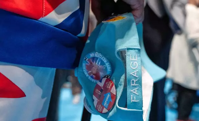 A member carrys a hat during the Reform party's annual conference at the National Exhibition Centre in Birmingham, England, Friday, Sept. 4, 2026. (AP Photo/Thomas Krych)