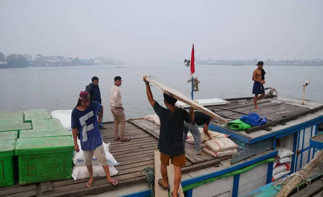 Workers load a boat amid the haze from forest fires at a pier in Pontianak, West Kalimantan, Indonesia, Monday, Sept. 14, 2026. (AP Photo/Tatan Syuflana)