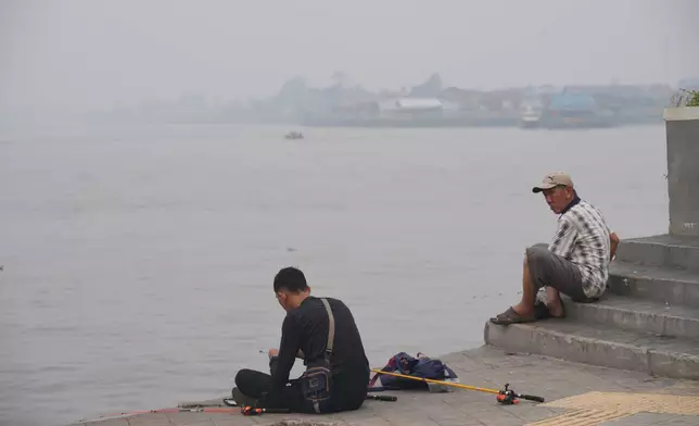 People fish at the bank of Kapuas River amid the thick haze from forest fires, in Pontianak, West Kalimantan, Indonesia, Monday, Sept. 14, 2026. (AP Photo/Tatan Syuflana)