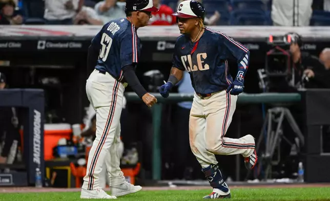 Cleveland Guardians third base coach Rouglas Odor, left, greets Jose Ramirez, right, after Ramirez's solo home run off Athletics relief pitcher Seth Johnson during the sixth inning of a baseball game, Friday, Sept. 18, 2026, in Cleveland. (AP Photo/Phil Long)
