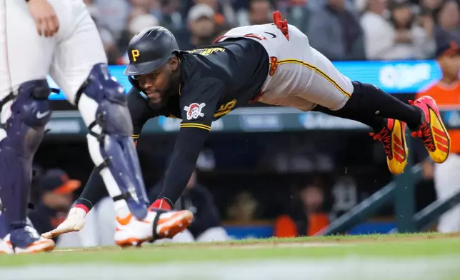 Pittsburgh Pirates' Oneil Cruz dives into home plate to score against the Detroit Tigers on a single hit by Ryan O'Hearn during the second inning of a baseball game Friday, Sept. 25, 2026, in Detroit. (AP Photo/Duane Burleson)