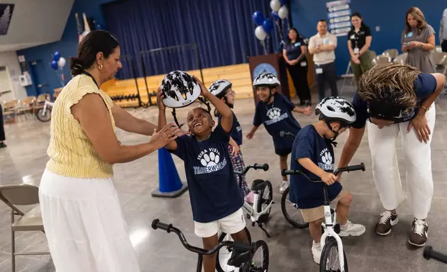 Kindergartner Carson Hagens, center, smiles as he removes his helmet after riding a bike during a learn-to-ride program at Terra Vista Elementary School in Rancho Cucamonga, Calif., Wednesday, Sept. 2, 2026. (AP Photo/Jae C. Hong)