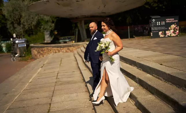Newlyweds Iryna Baranova, right, and Evhen Mytsyk leave after their wedding portrait session at the botanical gardens, on their wedding day in Kyiv, Wednesday, Sept. 2, 2026. (AP Photo/Francisco Seco)