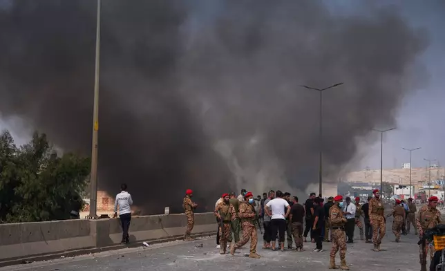 Syrian security forces and others gather as smoke rises after an explosion at what state media said was a weapons depot in the Burj al-Nimra area near Sarmada, in Idlib province, Syria, Wednesday, Sept. 9, 2026.(AP Photo/Omar Albam)