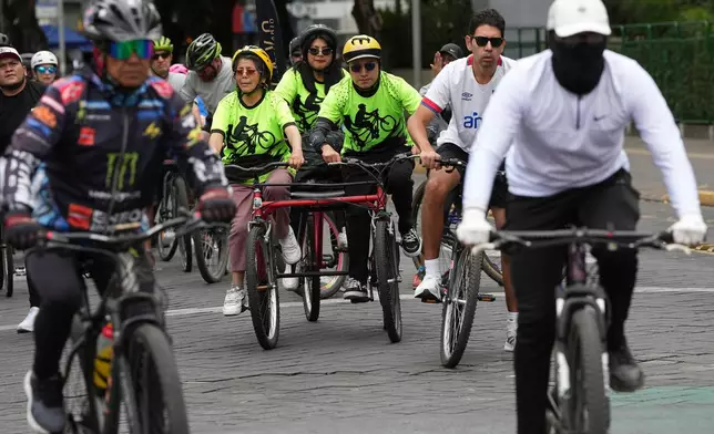 A volunteer with the "Ciegocleta" initiative guides a visually impaired participant, left, on a tandem bicycle in Quito, Ecuador, Sunday, Aug. 30, 2026. (AP Photo/Dolores Ochoa)