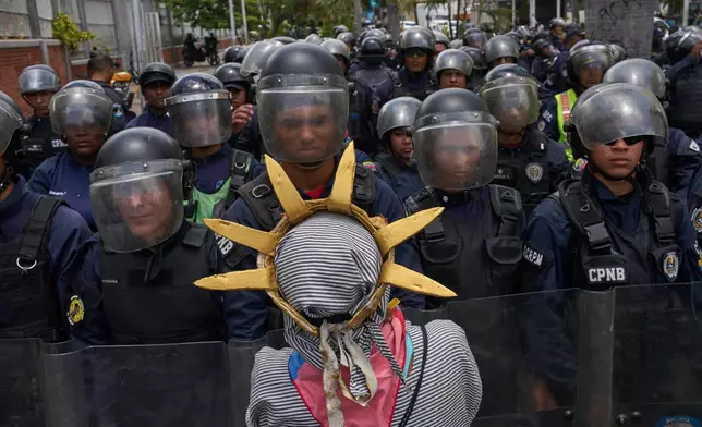 Paola Fernandez, dressed as statue of Liberty, speaks to national police members that are blocking a street toward to presidential palace during a march demanding for the release of all political prisoners in Caracas, Venezuela, Friday, Sept. 11, 2026. (AP Photo/Ariana Cubillos)