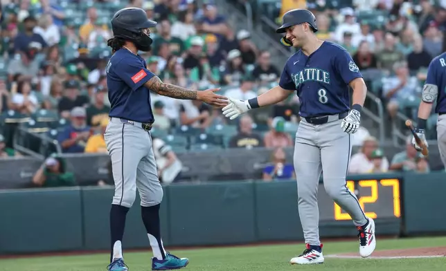 Seattle Mariners' Dominic Canzone (8) high-fives J.P. Crawford, left, after hitting a two-run home run during the first inning of a baseball game against the Athletics Saturday, Sept. 12, 2026, in West Sacramento, Calif. (AP Photo/Sara Nevis)
