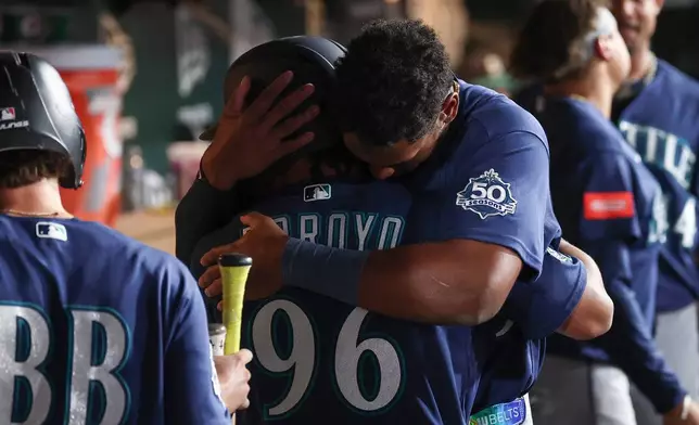 Seattle Mariners' Lazaro Montes, right, hugs Michael Arroyo (96) after his first major-league hit during the fourth inning of a baseball game against the Athletics Saturday, Sept. 12, 2026, in West Sacramento, Calif. (AP Photo/Sara Nevis)