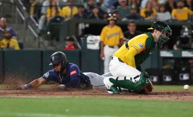 Athletics catcher Jonah Heim, right, attempts to put out Seattle Mariners' Michael Arroyo, left, at home during the fourth inning of a baseball game Saturday, Sept. 12, 2026, in West Sacramento, Calif. (AP Photo/Sara Nevis)