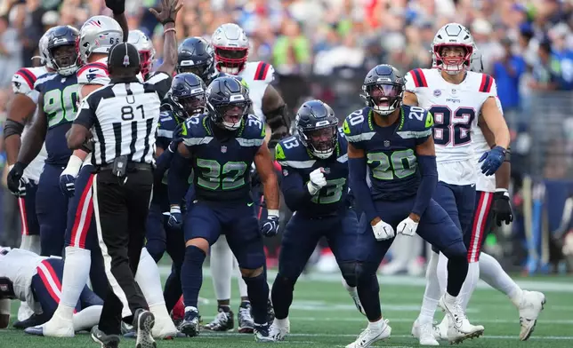 Seattle Seahawks safety Julian Love (20), celebrates with linebackers Drake Thomas (32) and Ernest Jones IV (13) after tackling New England Patriots running back Rhamondre Stevenson as New England Patriots tight end Eli Raridon (82) looks on during the first half of an NFL football game, Wednesday, Sept. 9, 2026, in Seattle. (AP Photo/Lindsey Wasson)