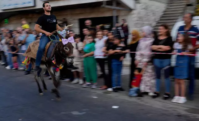 A participant races his donkey during the summer donkey race in Roum village, southern Lebanon, Sunday, Sept. 6, 2026. (AP Photo/Hussein Malla)