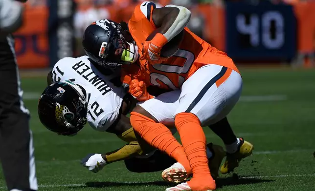 Denver Broncos running back Jonah Coleman (20) is hit by Jacksonville Jaguars cornerback Travis Hunter (12) after Coleman caught a pass in the first half of an NFL football game in Denver, Sunday, Sept. 20, 2026. (AP Photo/Eric Lutzens)